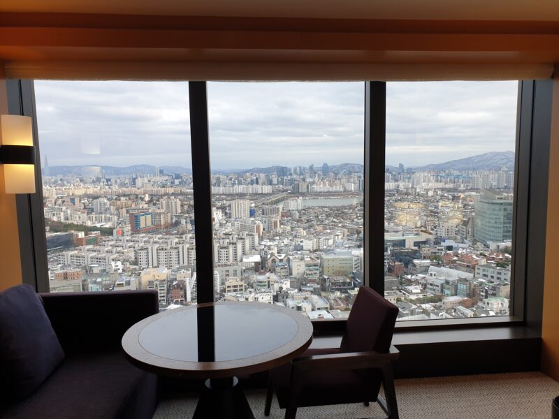 a table and chairs in front of a window overlooking a city