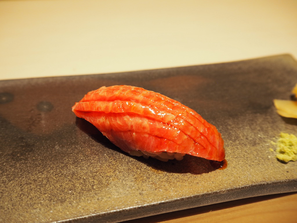 a piece of sushi on a black surface
