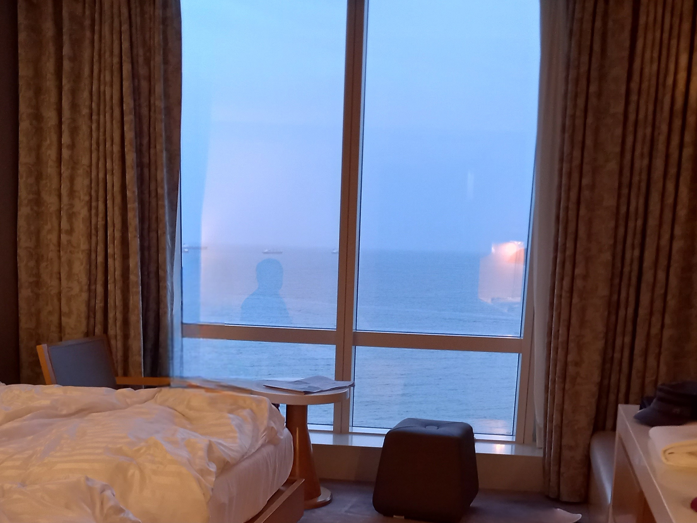a bedroom with a view of the ocean and a sunset