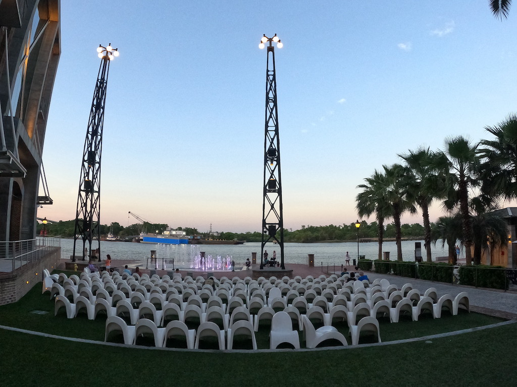 a large group of chairs in a courtyard by a body of water