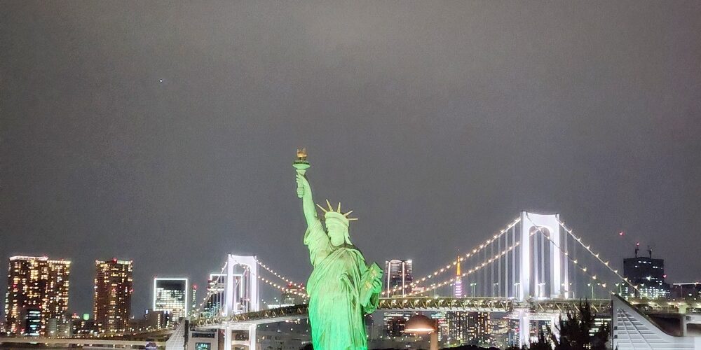 a statue of a person holding a torch in front of a city