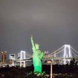 a statue of a person holding a torch in front of a city