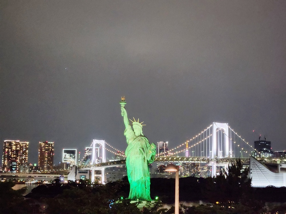 a statue of a person holding a torch in front of a city