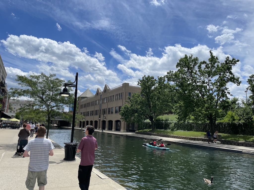 people on a dock by a body of water with a boat in it