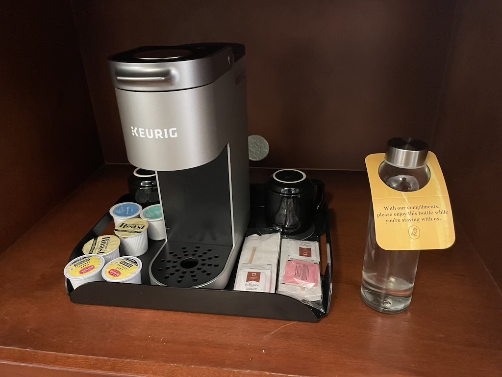 a coffee maker and a glass of water on a table