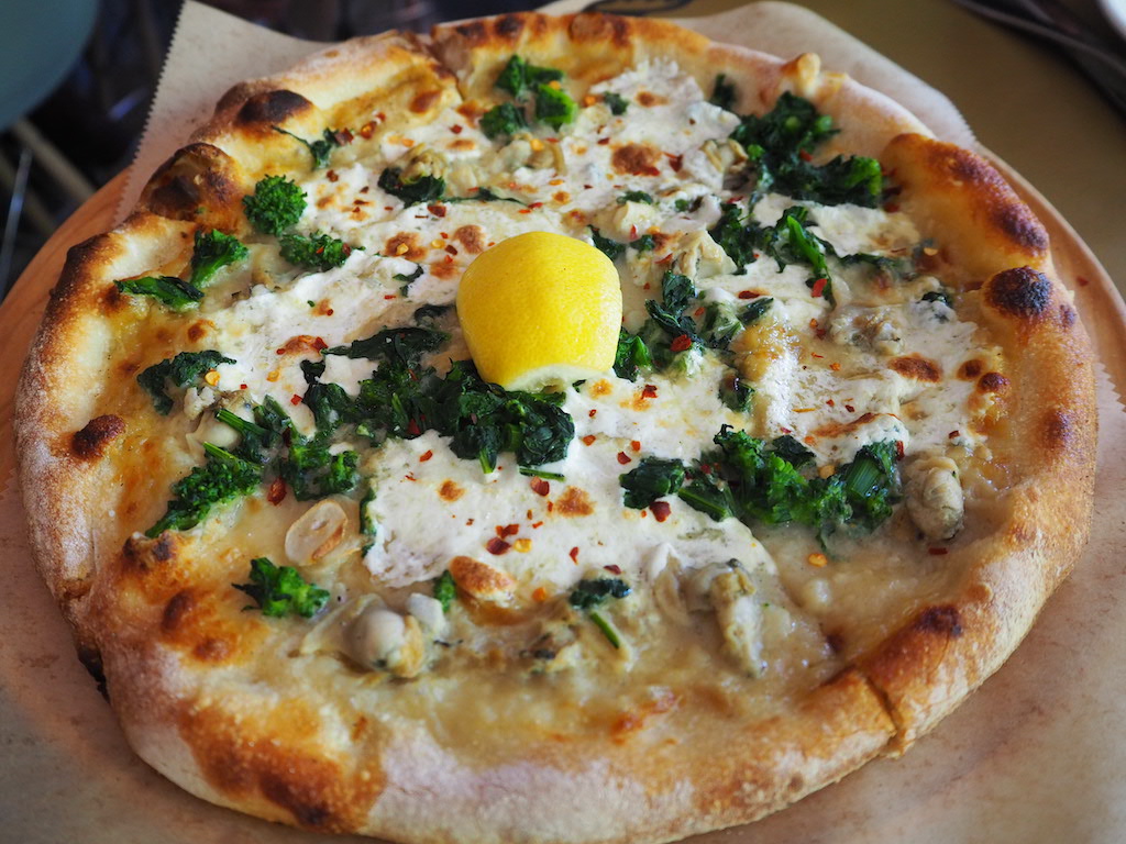 a pizza with eggs and broccoli on it