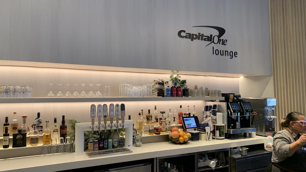 a person sitting at a counter with a laptop and bottles of alcohol