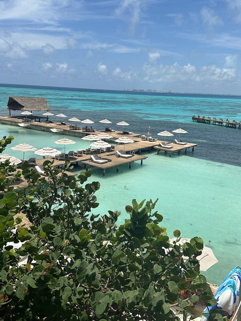 a dock with umbrellas and chairs on it next to a body of water