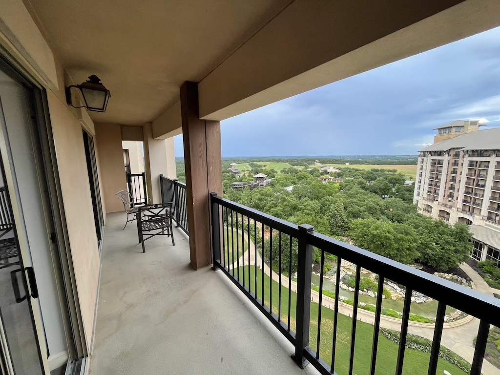 a balcony with a view of a forest and a building