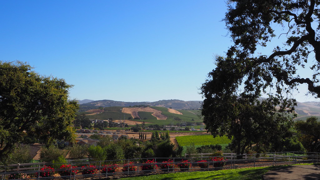 a fenced in field with trees and hills in the background