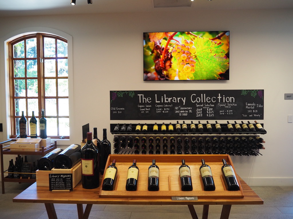 a table with bottles of wine on it and a sign above it