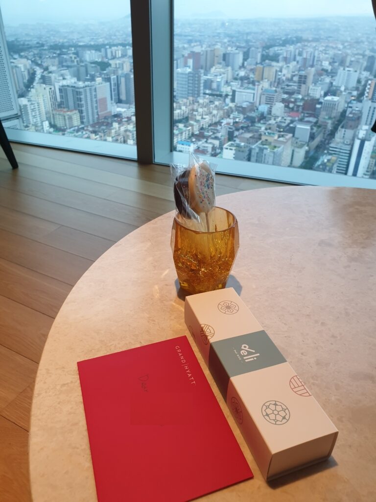 a chocolate ice cream cone on a table with a box and a city skyline