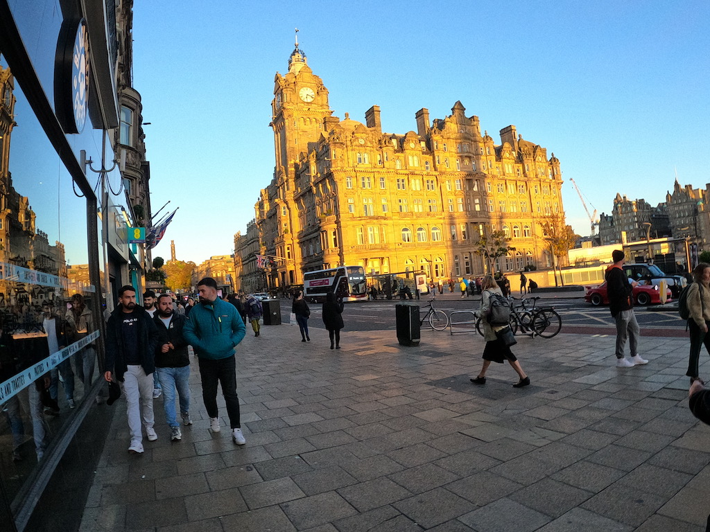 a group of people walking on a street in front of a large building