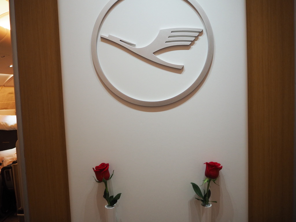 a white wall with a white circle and a red rose in front of it