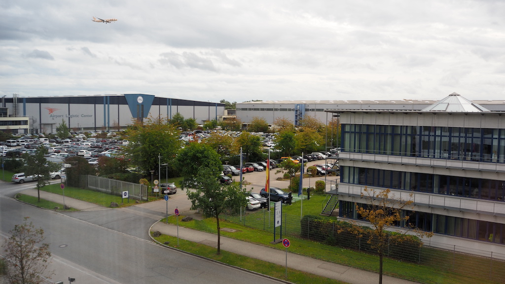 a building with a parking lot and a helicopter flying over it