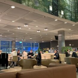 a group of people sitting in a room with chairs and tables