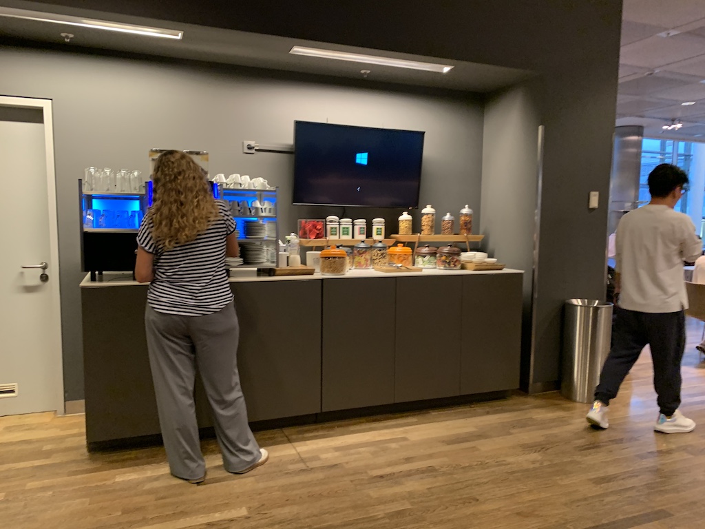 a woman standing in front of a counter with a man and a television