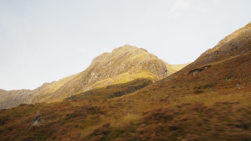 a grassy hill with a person walking on it