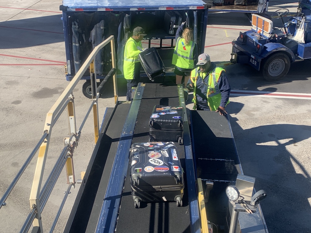 a group of people standing next to a truck with luggage