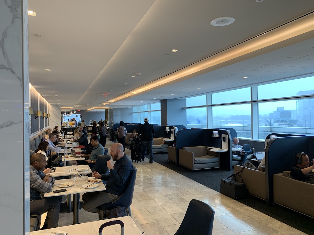 a group of people sitting around a table in a room with large windows