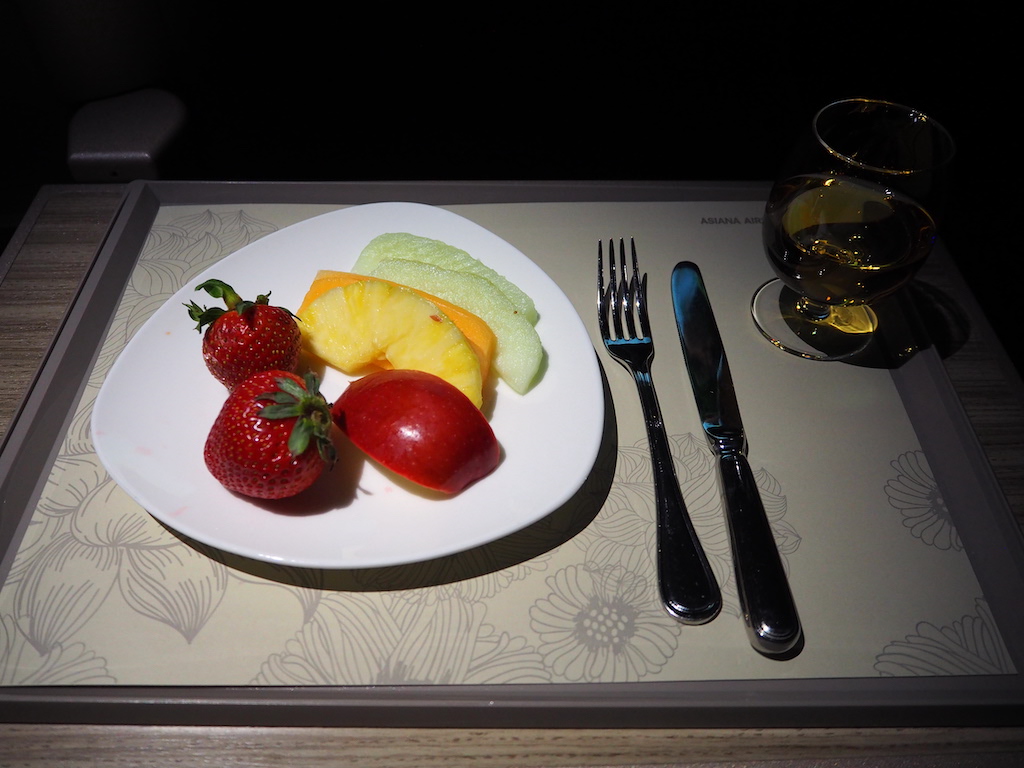 a plate of fruit and a glass of wine on a table