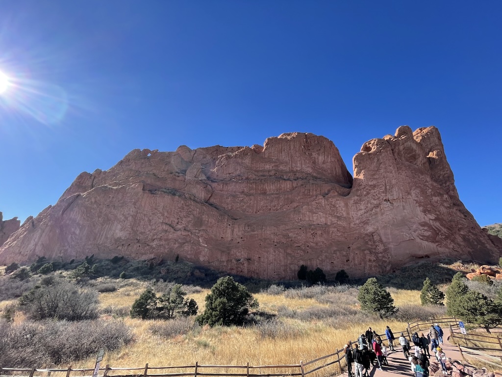 a group of people on horses in front of a large rock formation