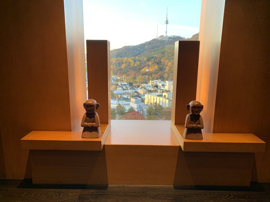 a couple of statues in front of a window overlooking a city