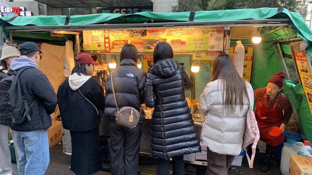 a group of people standing outside a food stand