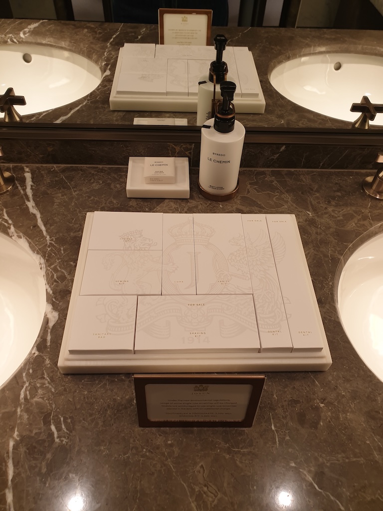 a bathroom counter with a sink and a bottle of perfume