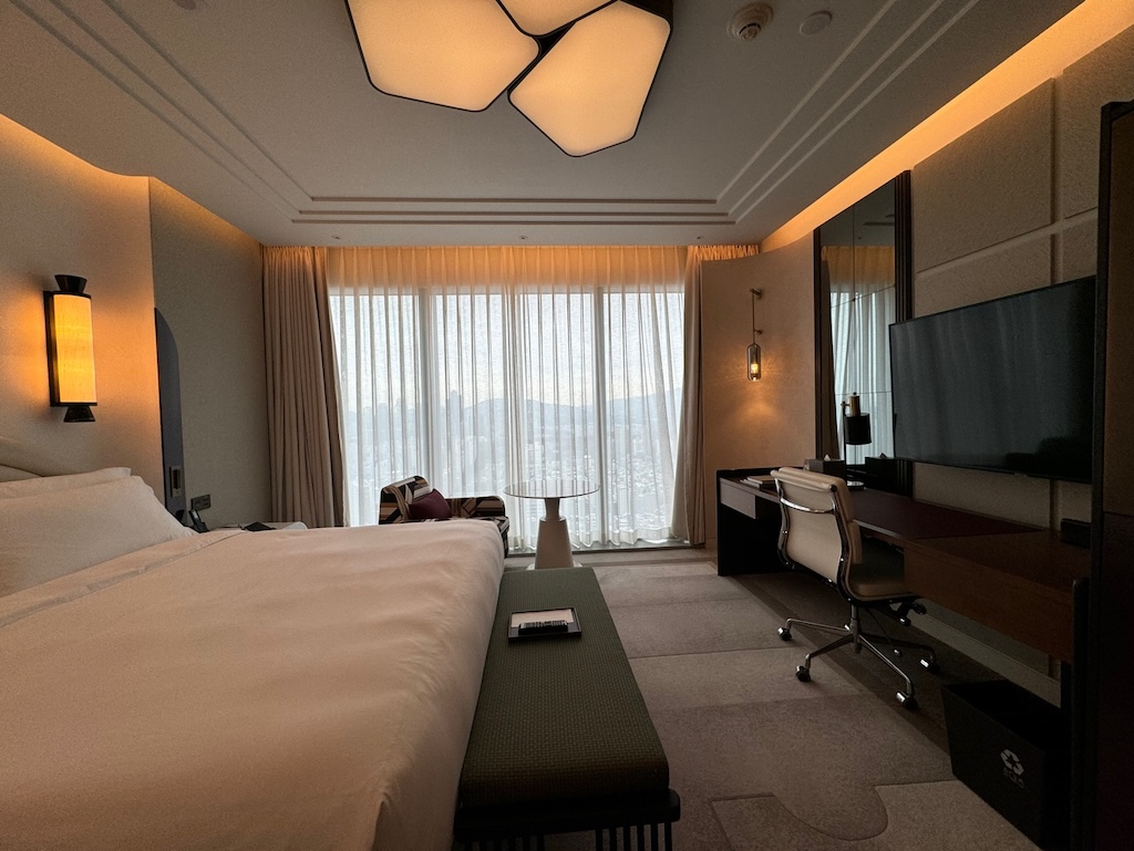 a hotel room with a bed desk and a large window