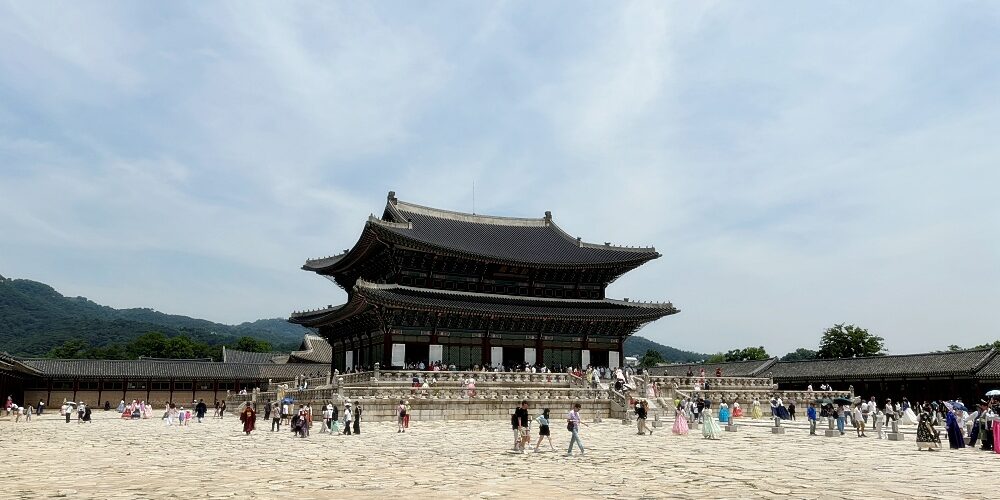 a large group of people at a large building with Gyeongbokgung in the background