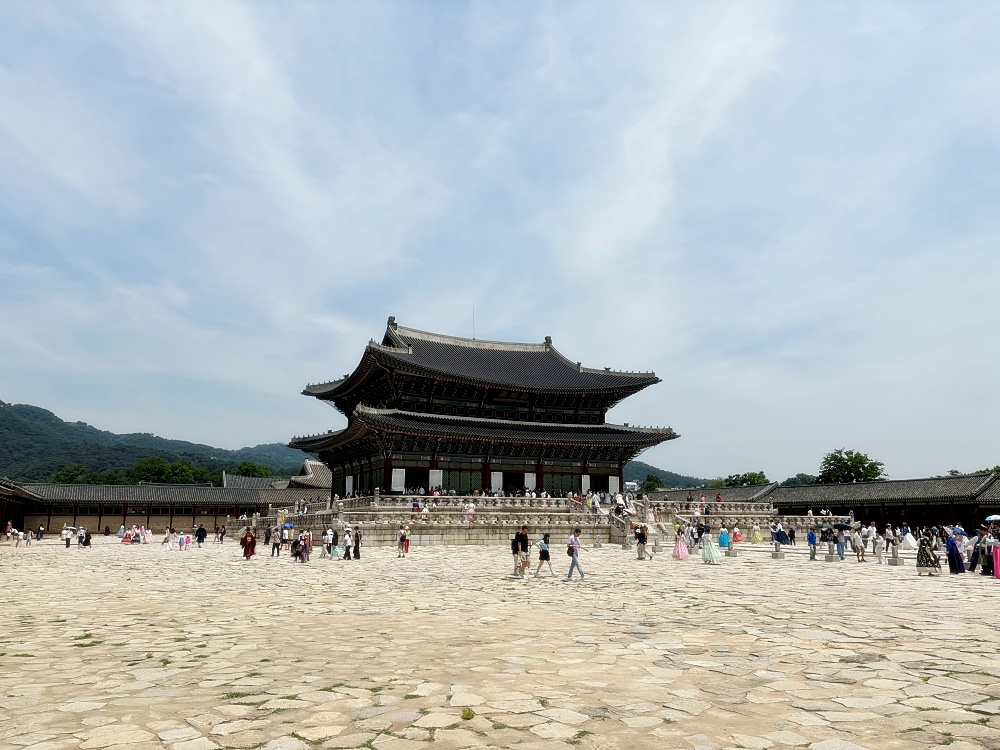 a large group of people at a large building with Gyeongbokgung in the background