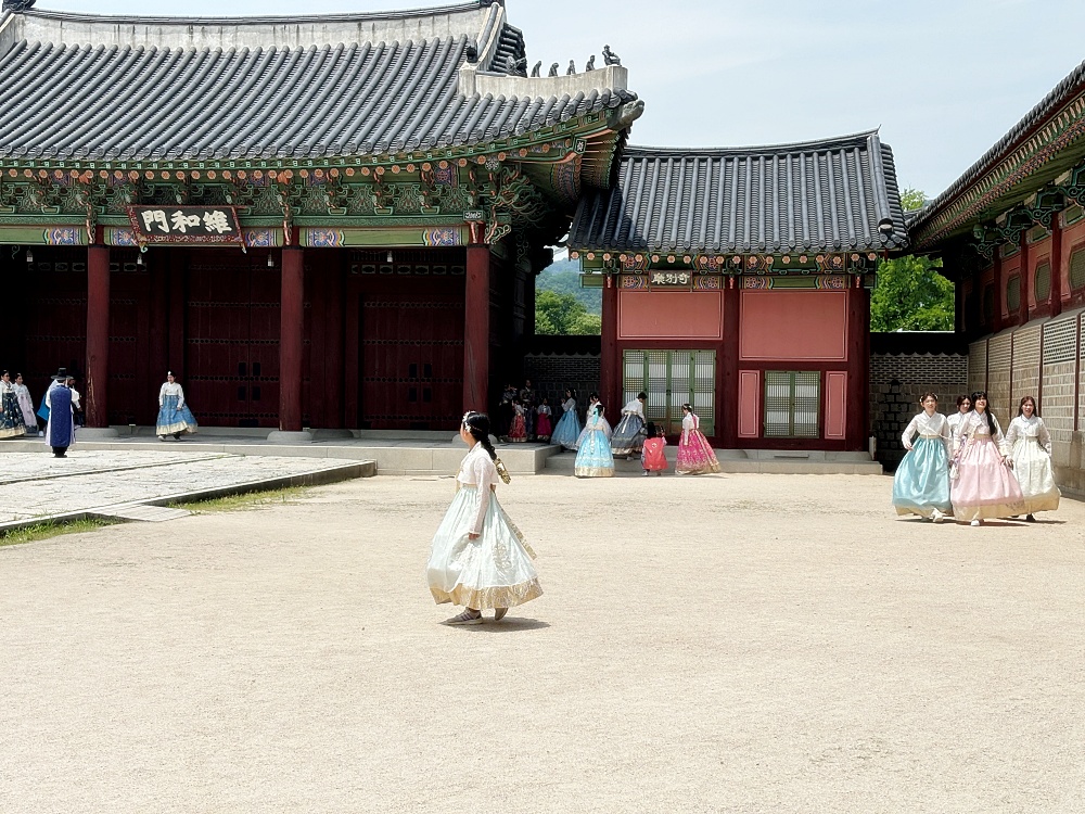 a group of women in dresses walking in front of a building