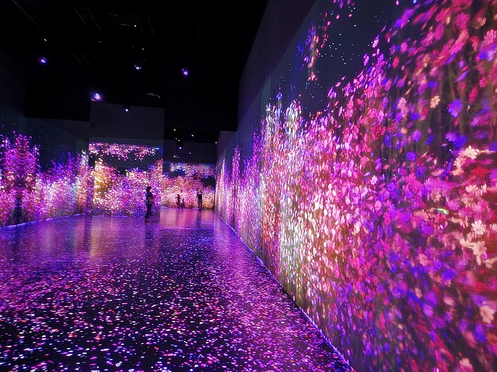 a group of people walking through a tunnel with pink lights