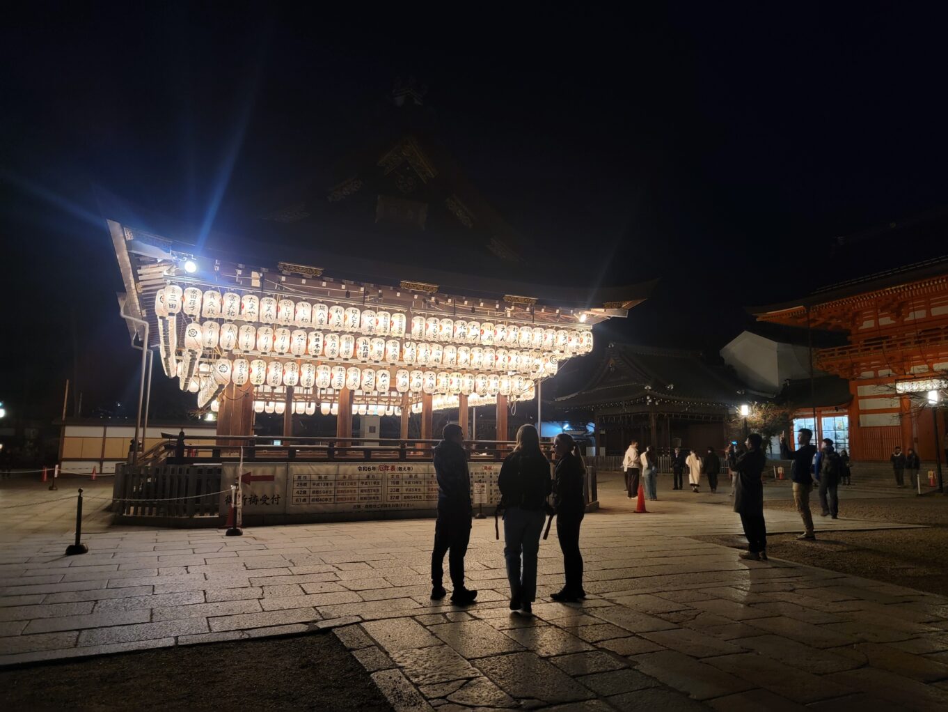 a group of people standing around a lighted structure with Gyeongbokgung in the background