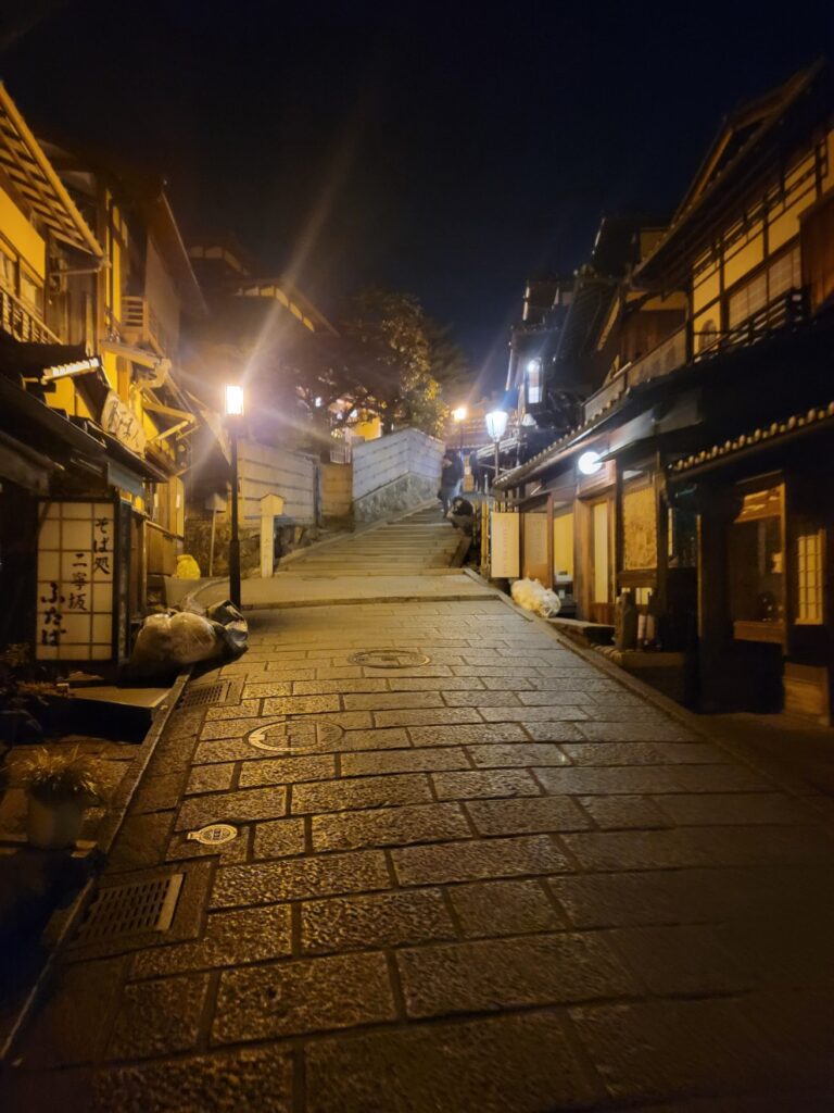 a stone walkway between buildings at night