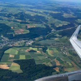 an airplane wing over a green landscape