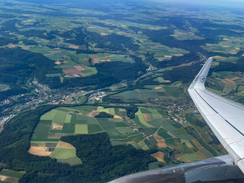 an airplane wing over a green landscape