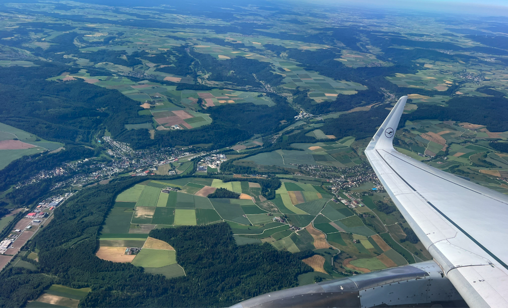 an airplane wing over a green landscape