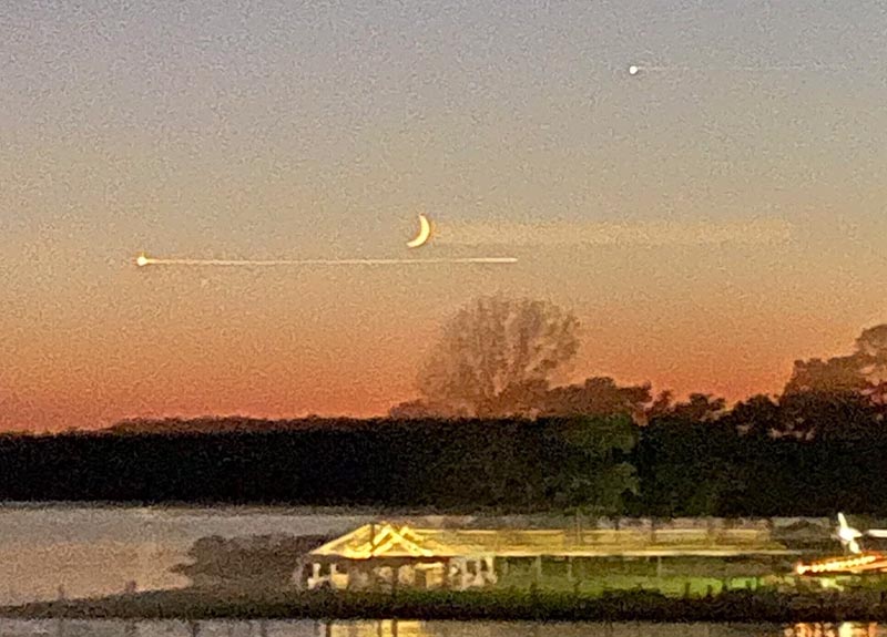 a couple of kites flying in the sky over a lake