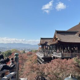 a group of people sitting on a bench in front of Kiyomizu-dera