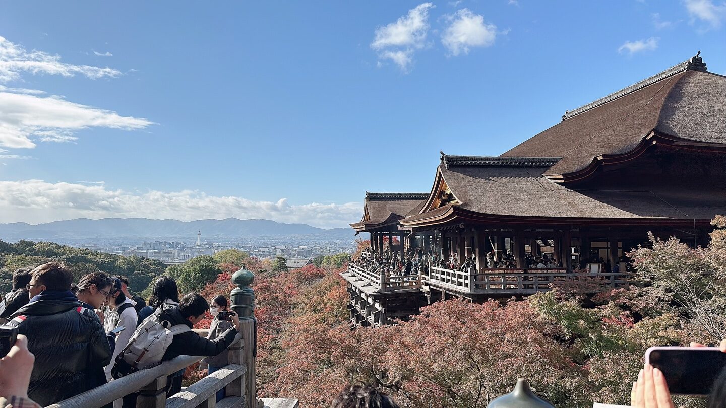 a group of people sitting on a bench in front of Kiyomizu-dera