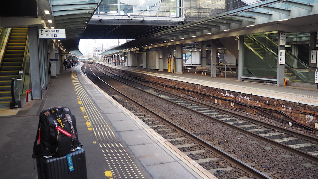 a train station with a couple of people waiting for their luggage