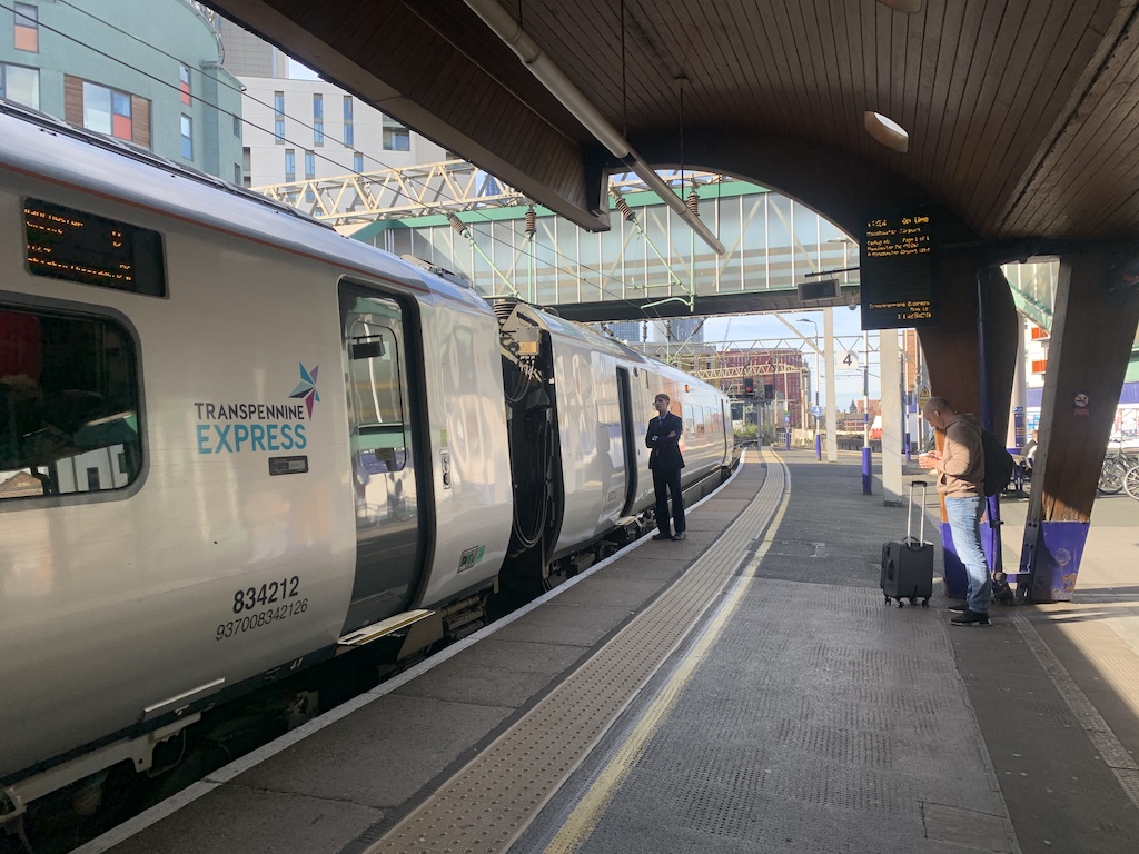 a couple of people stand near a train at a train station