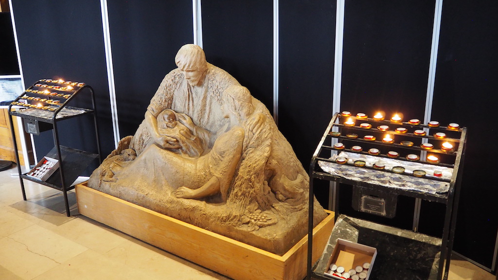 a statue of a person with a beard and a hat with a lit candle in front of him