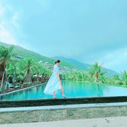 a person in a white dress walking by a pool