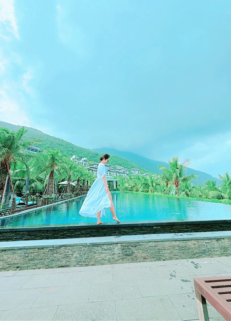 a person in a white dress walking by a pool