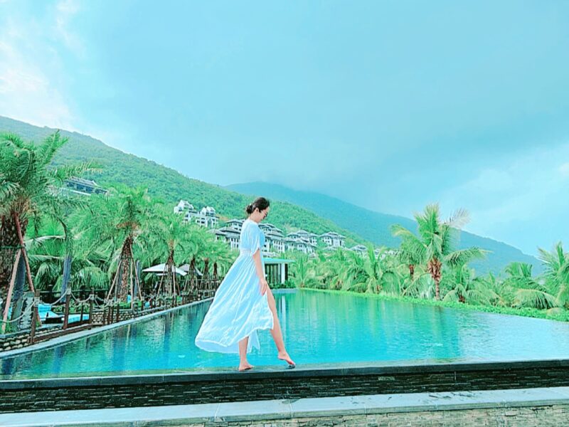 a person in a white dress walking by a pool