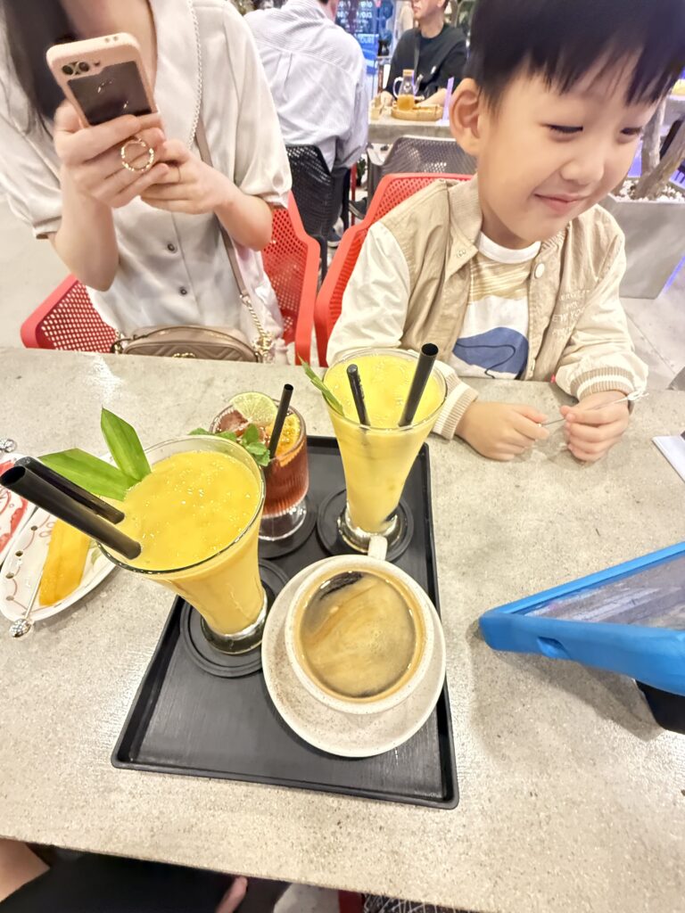 a child sitting at a table with food and drinks