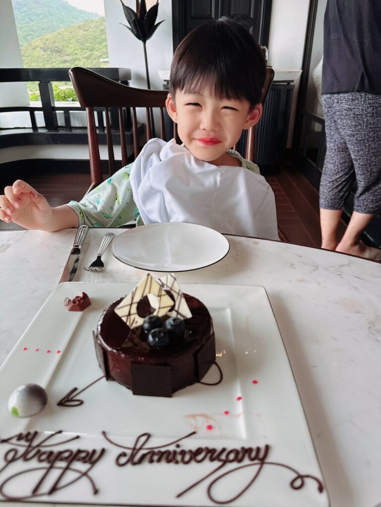 a boy sitting at a table with a cake